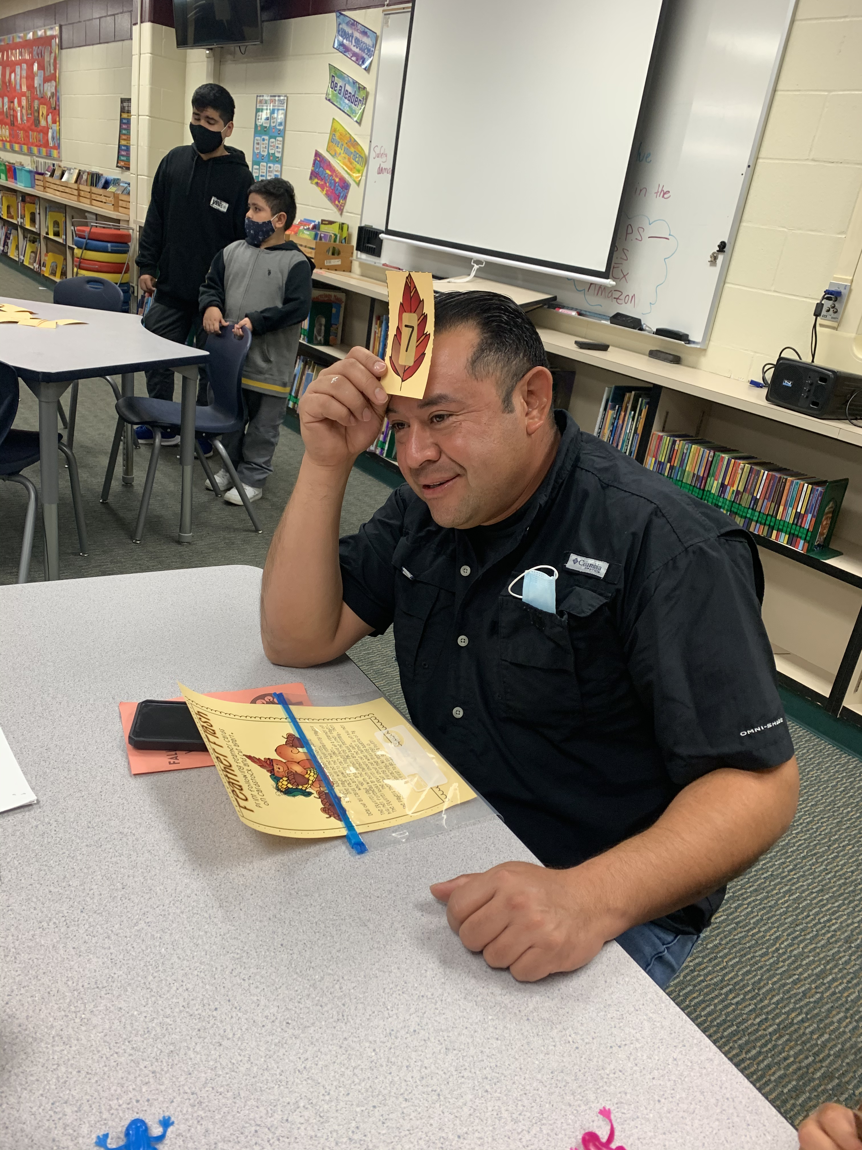 Father holding a card to forehead while playing math game.