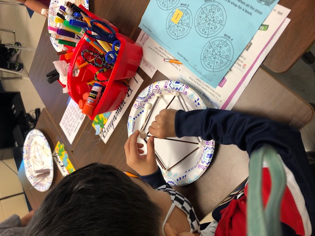 Student building a pyramid with sticks.