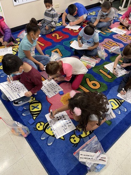 Students sitting on carpet working on Math problems