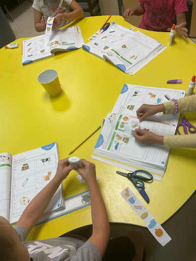 Student gluing pictures in a book. 