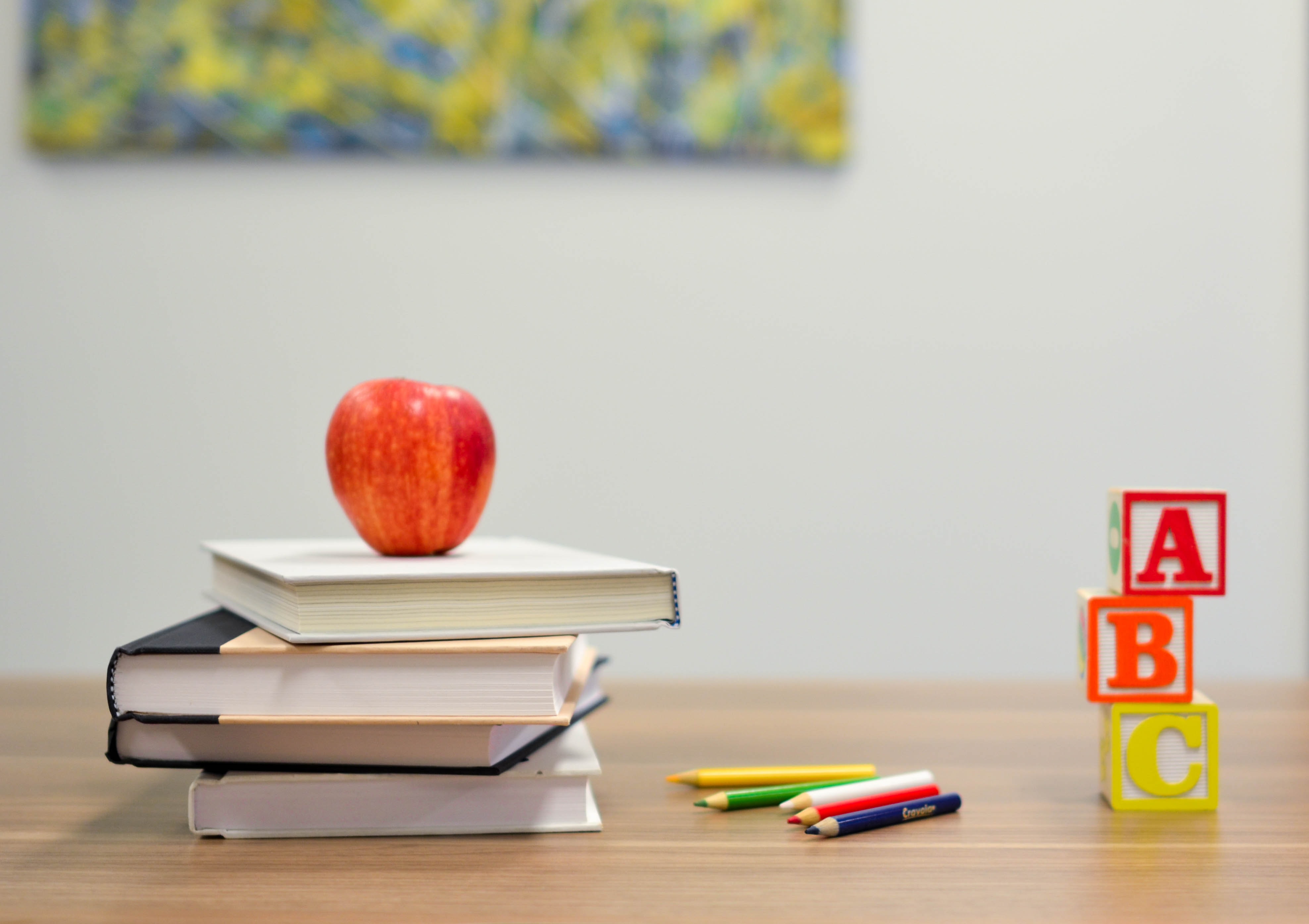 Portrait of a red apple on stack of books next to ABC blocks