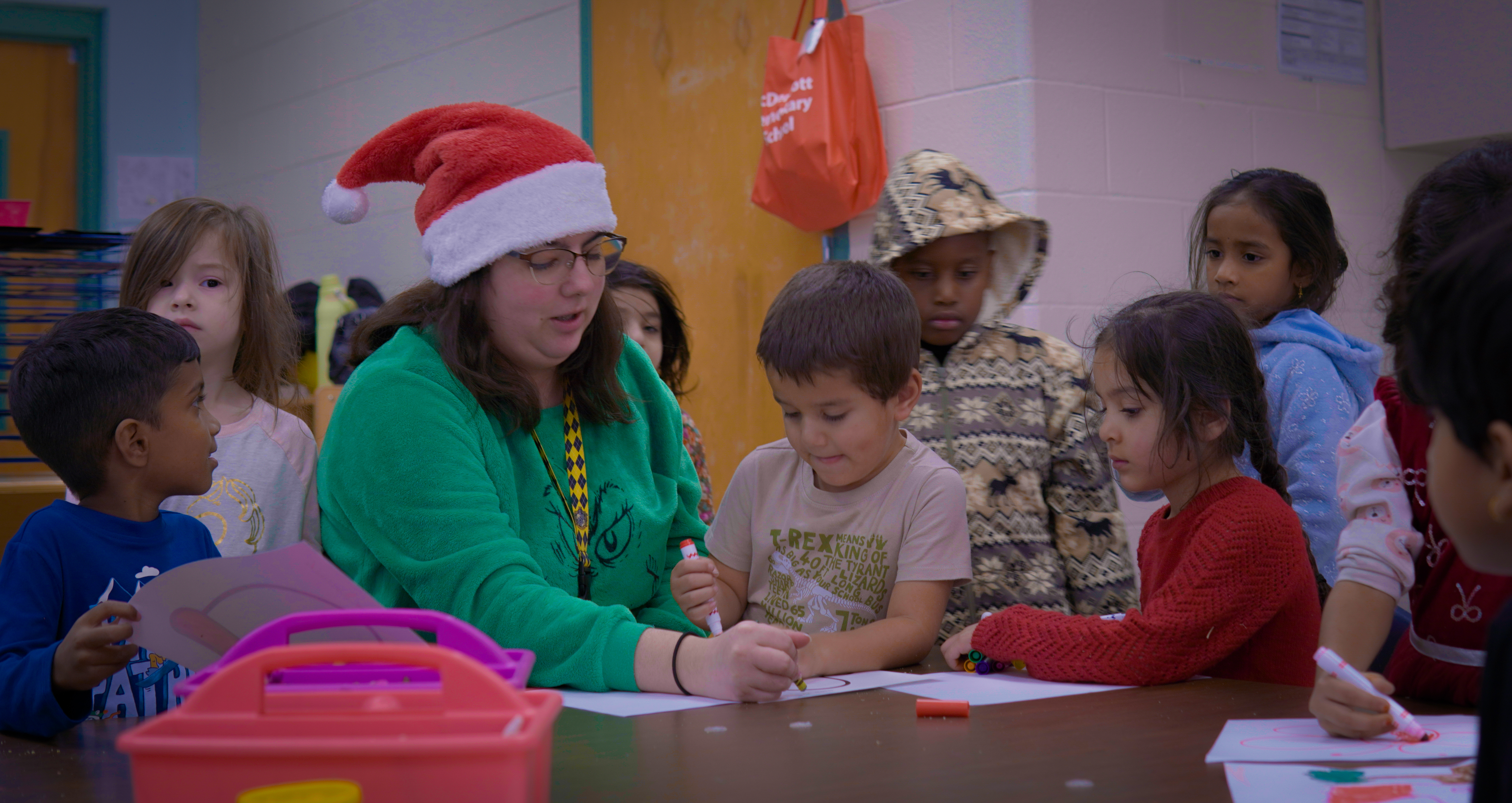 Pre-K Teacher, Ms Prosperi, sitting at a table with her students