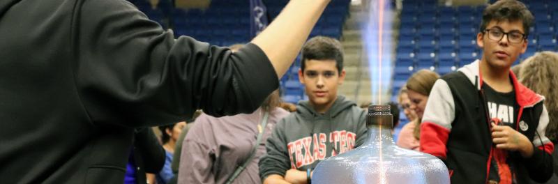 fire erupting out of a water jug while students watch