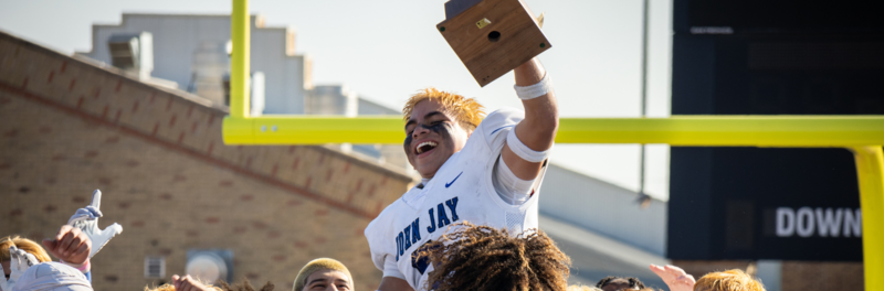 Varsity Football Players Hoisting a Trophy