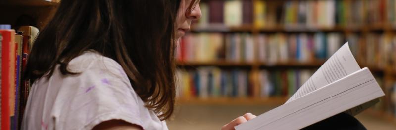 Girl reading a book in the library. Photo by Eliot Reyna on Unsplash