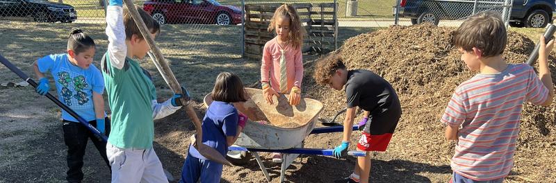 Students with shovels working in the campus garden