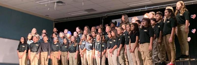 group of students singing in a school choir dressed in kahkis and school shirts.
