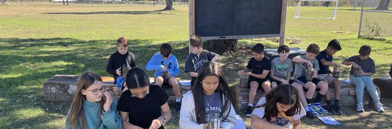 students sitting in the outdoor classroom on a nice sunny day