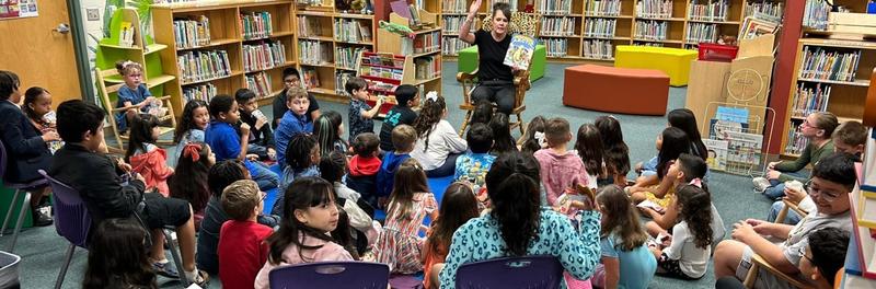 Student's listening to teacher read a book during Library Night.