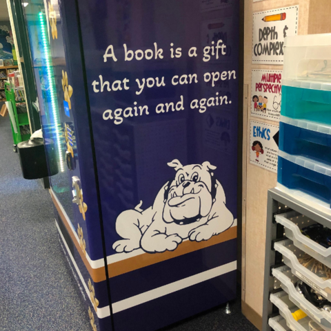 Right side of Book Vending Machine with "A book is a gift that you can open again and again" quote and Helotes Bulldog logo