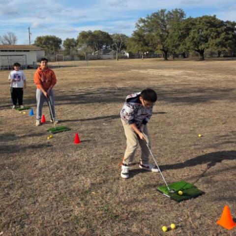 Three boys preparing to hit golf ball.