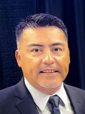 Portrait of Richard Yzaguirre with a black background.