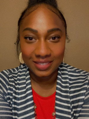 Ms. Mallard wearing red blouse with gold ear rings and black hair
